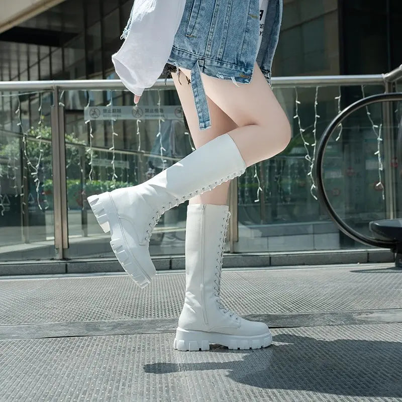 Person wearing white knee-high boots on a city street.