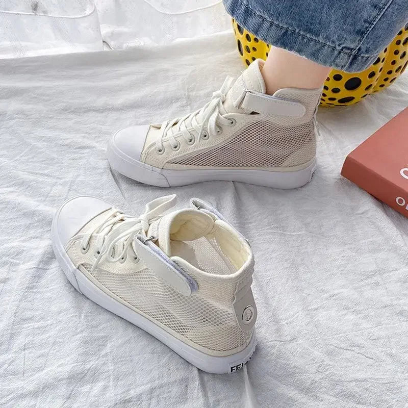 White high-top sneakers on a light gray surface with a person wearing them.
