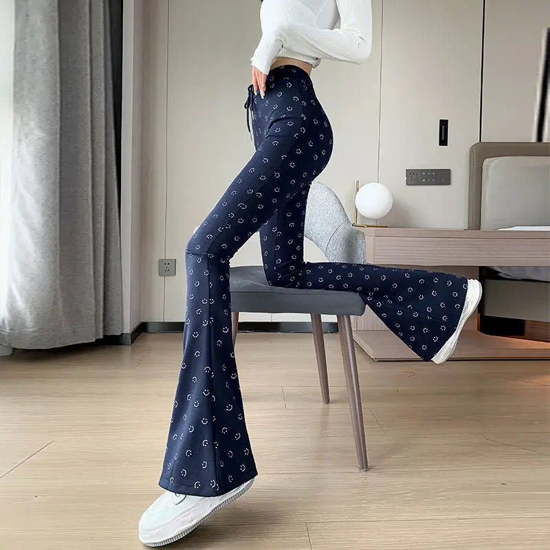 Person wearing navy bell-bottom pants with white patterns in a room.