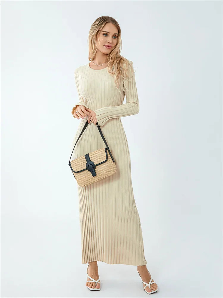 Woman wearing a beige ribbed dress holding a beige handbag on a white background
