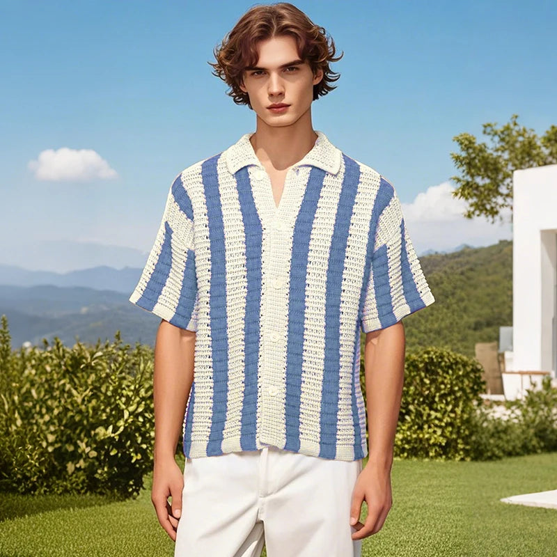 Man wearing a blue and white striped shirt in an outdoor setting with greenery and a clear sky.