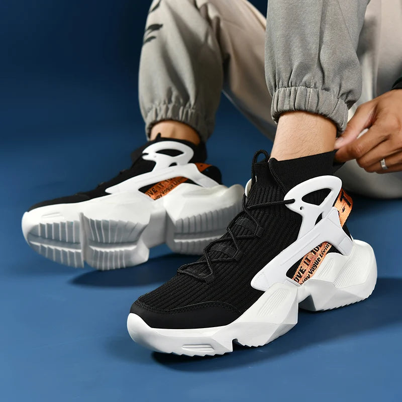 Black and white sneakers with orange accents worn by a person on a blue background