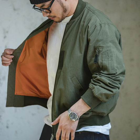 Man wearing a green bomber jacket with a neutral background
