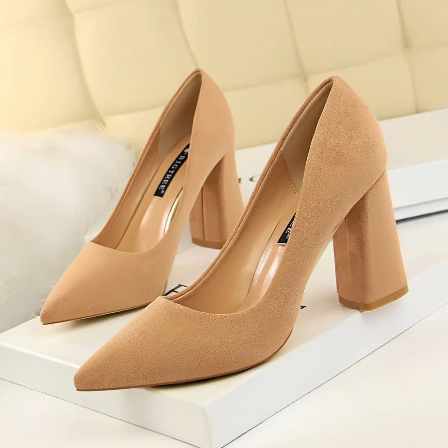 Pair of beige high-heeled shoes on a white surface with a light background