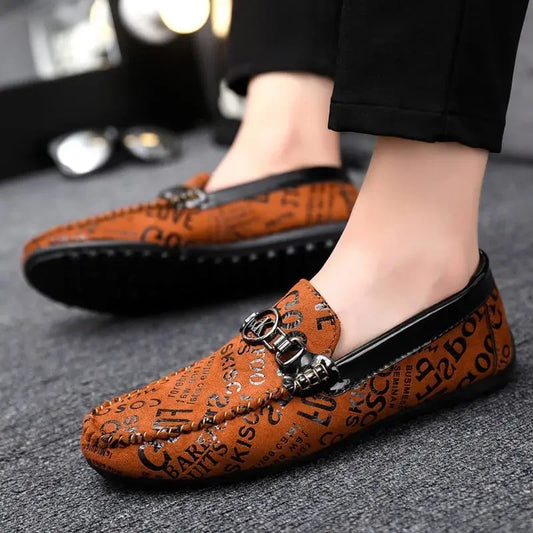 Brown loafers with decorative elements worn by a person on a gray surface.