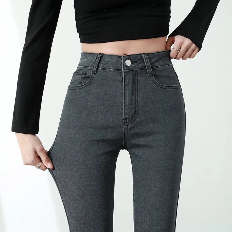 Person wearing high-waisted dark gray jeans with a plain background