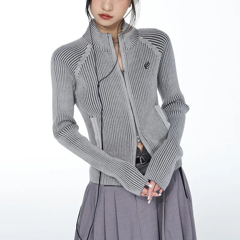Person wearing a gray ribbed sweater with a brand logo on a white background