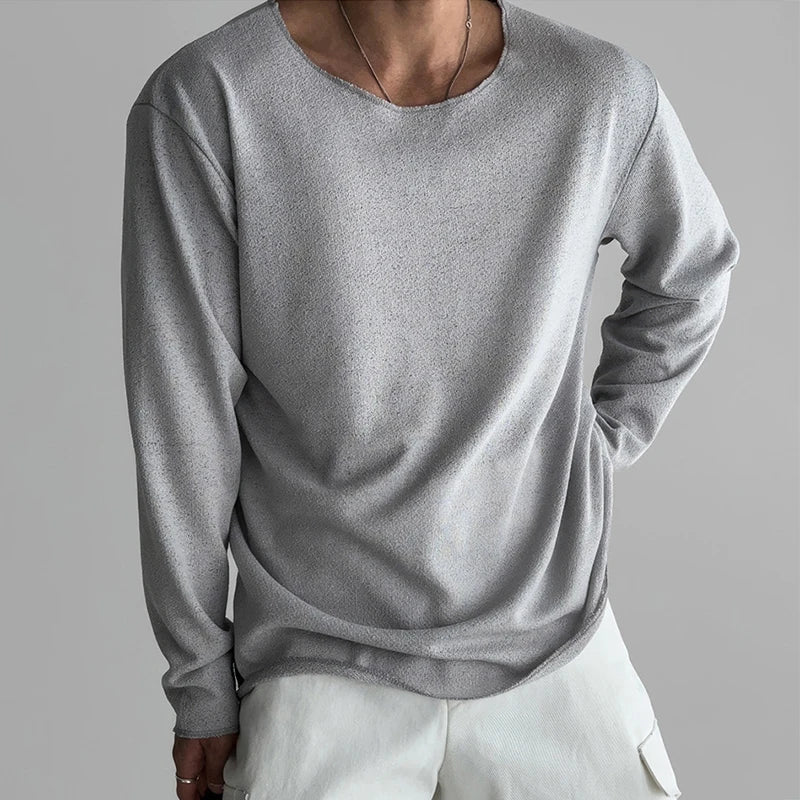 Person wearing a gray long-sleeve shirt and white pants on a gray background