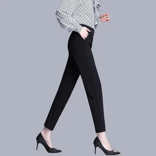 Person wearing black pants and a patterned blouse on a gray background