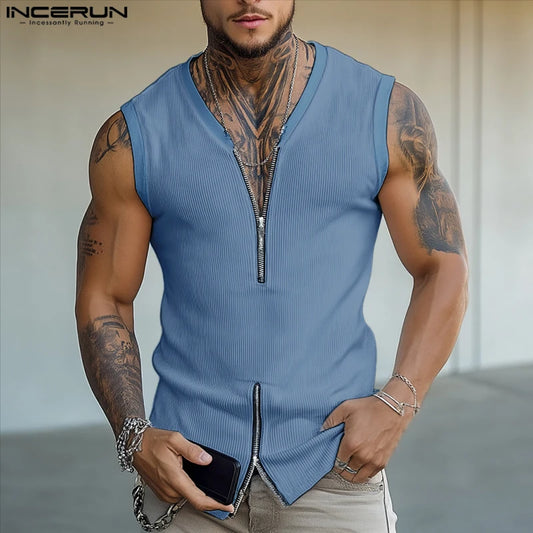 Man wearing a blue sleeveless zip-up shirt with tattoos on arms and neck, holding a phone.