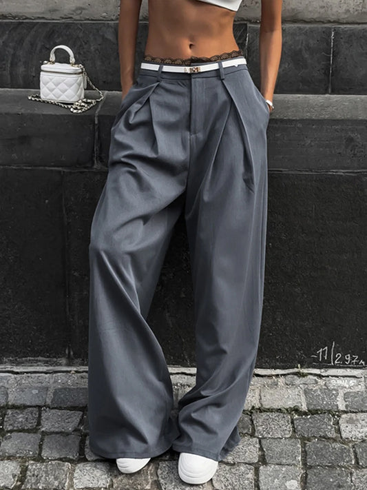 Person wearing wide-leg gray pants standing against a black wall.