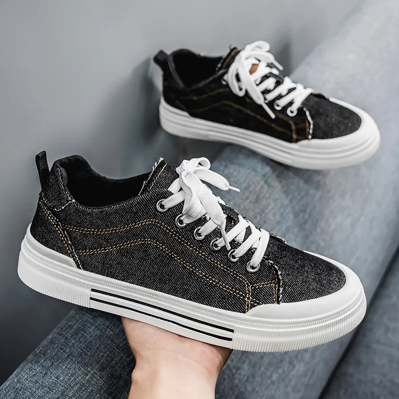 Black sneakers with white laces and soles on a gray surface