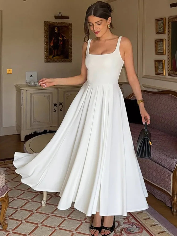 Woman in a white dress standing in an elegant room with decorative elements.