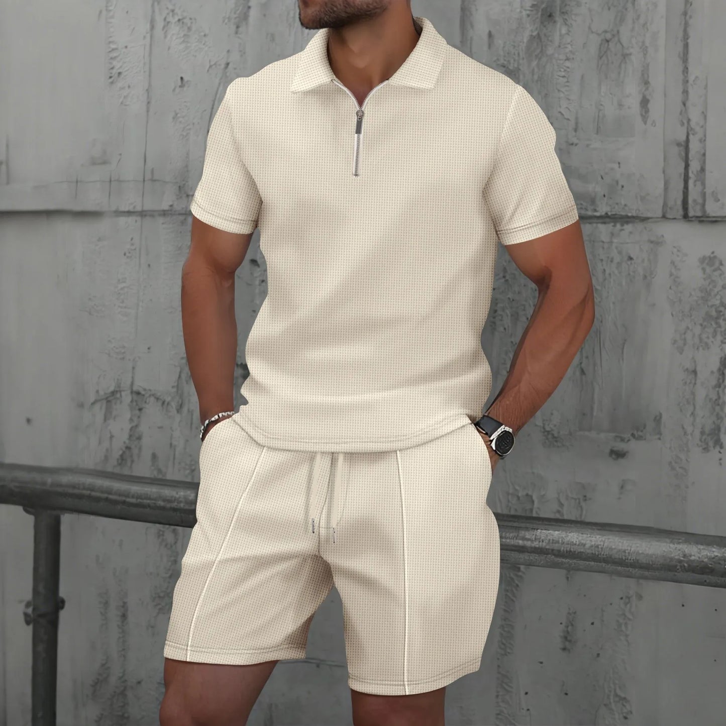 Man wearing a beige polo shirt and shorts set against a textured wall.