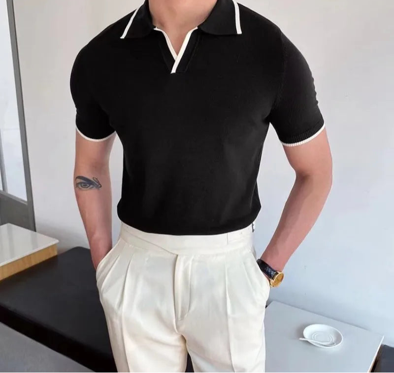 Person wearing a black polo shirt with white trim and white pants in an indoor setting.