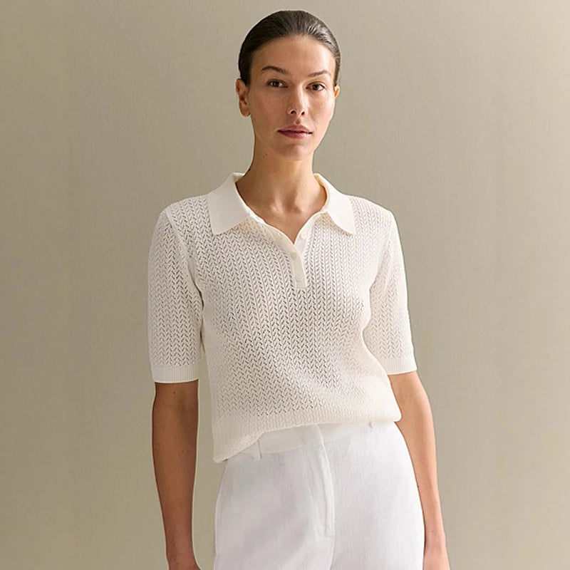 Woman wearing a white knit top and white pants against a beige background