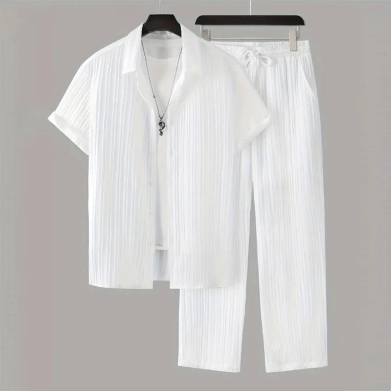 White pleated shirt and pants set on hangers against a gray background