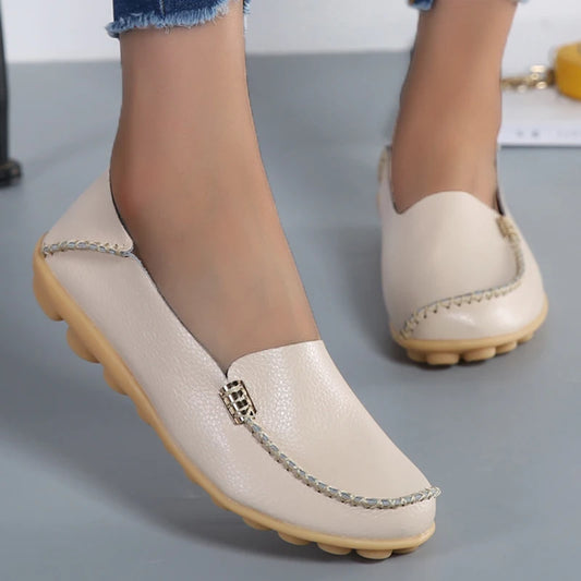 Beige loafers with a decorative chain on a gray background