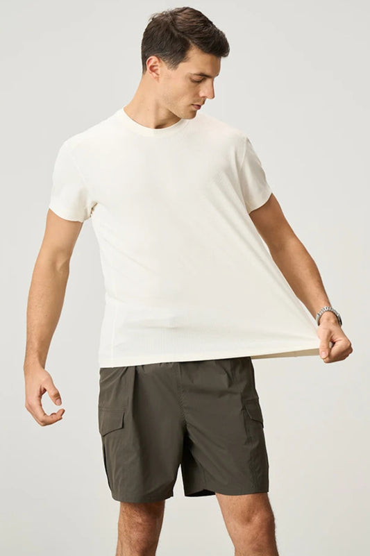 Man wearing a white t-shirt and green shorts on a plain background