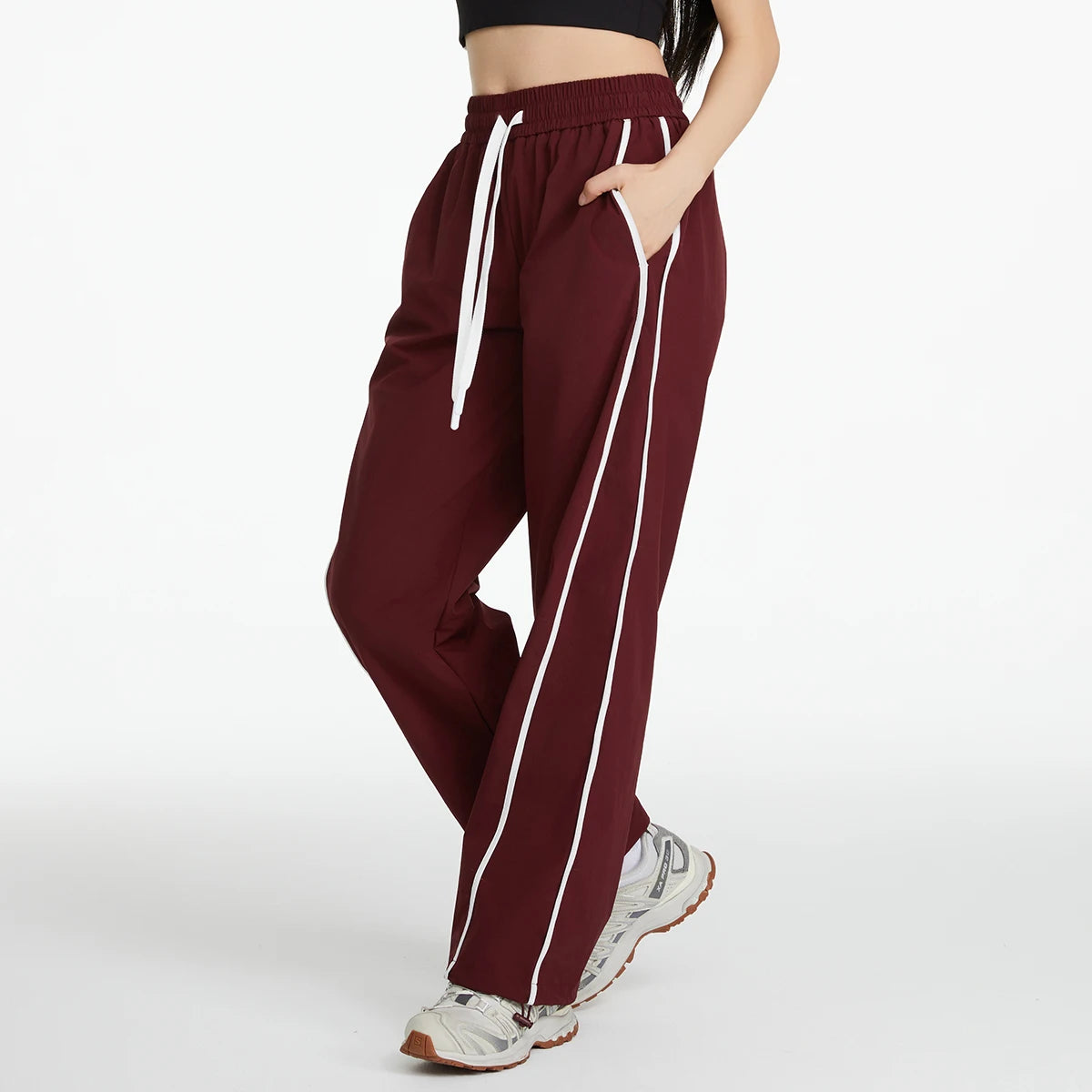 Maroon track pants with white stripes worn by a person on a white background
