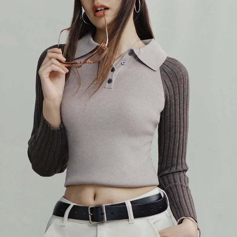 Woman wearing a ribbed knit sweater with a collar and long sleeves, holding glasses.