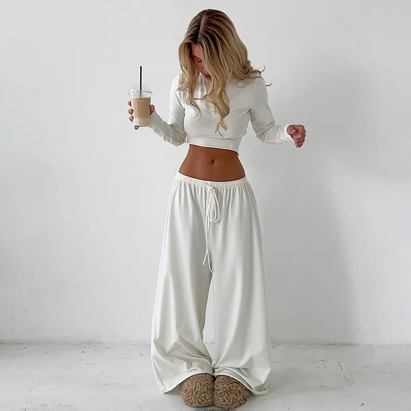 Woman wearing a white outfit holding a drink against a plain background