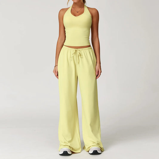 Person wearing a light yellow outfit with a halter top and wide-leg pants on a white background