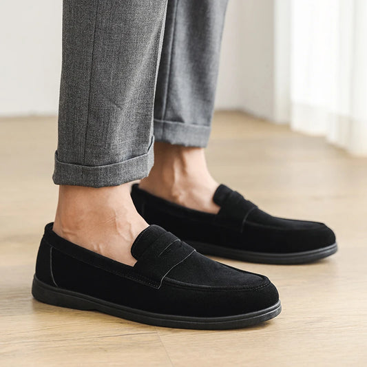 Person wearing black loafers on a wooden floor