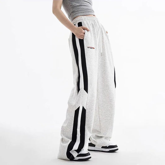 White sweatpants with black stripes worn by a person on a white background