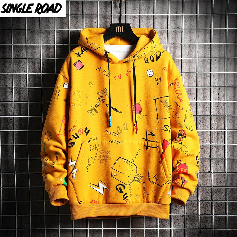 Yellow hoodie with various text and graphic designs on a tiled wall background