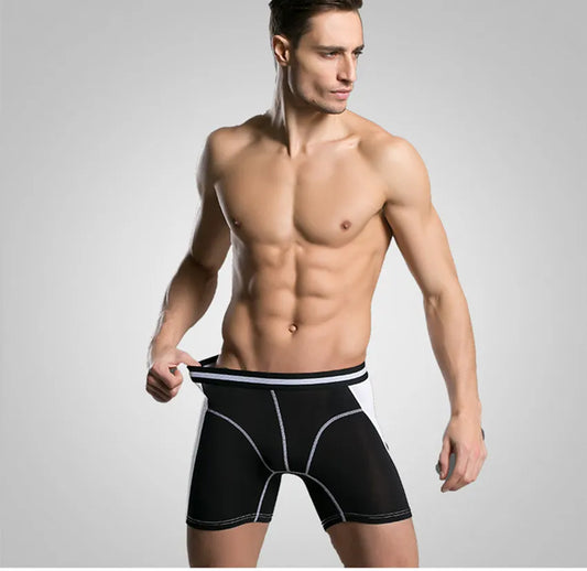 Man wearing black boxer briefs against a gray background