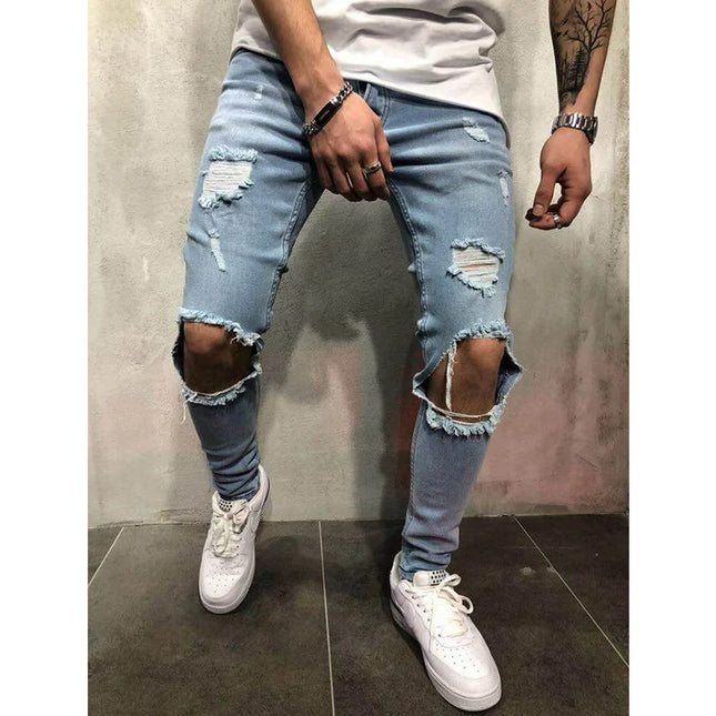 Person wearing light blue ripped jeans and white sneakers against a plain background