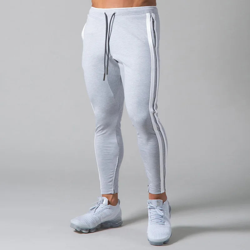 Light gray jogger pants with white stripes on a plain background