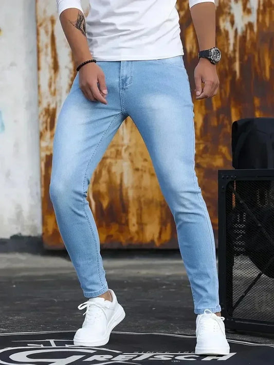 Person wearing light blue jeans and white sneakers against a rusty metal background