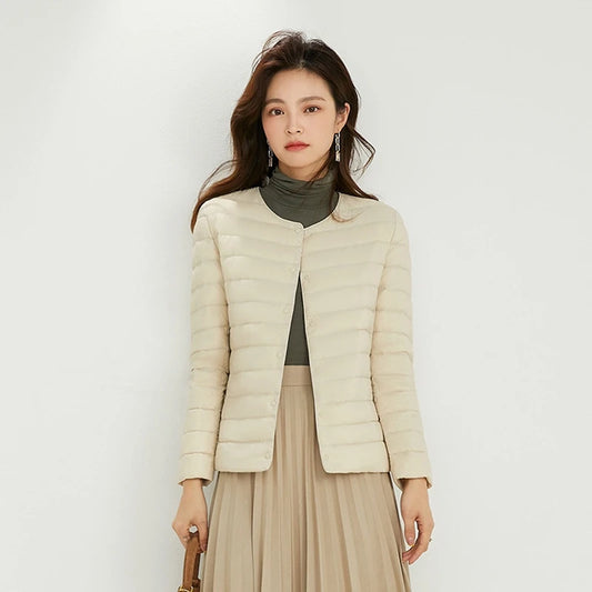 Woman wearing a beige puffer jacket against a white background