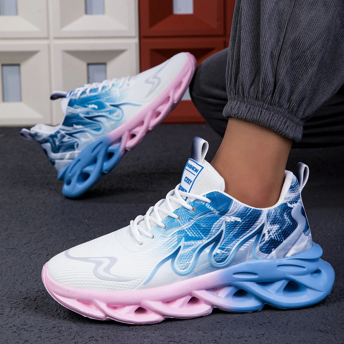 Blue and pink sneakers worn by a person on a dark surface with a blurred background