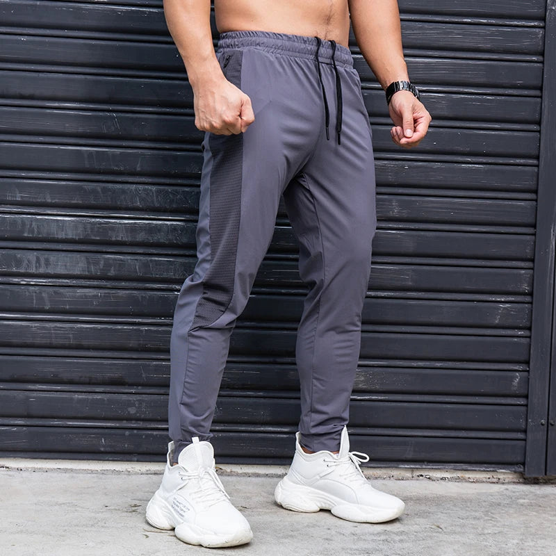 Person wearing gray jogger pants and white sneakers in front of a black metal shutter.