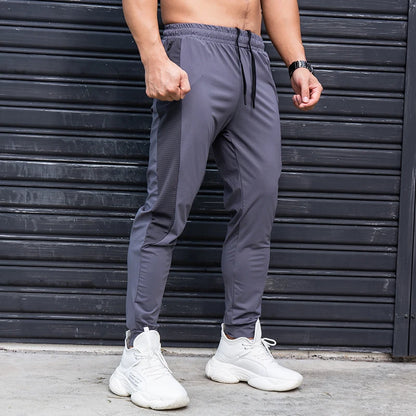 Person wearing gray jogger pants and white sneakers in front of a black metal shutter.