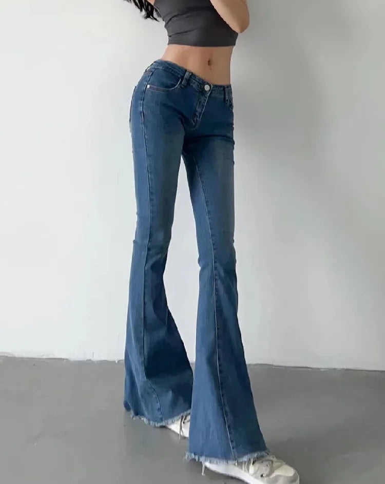 Person wearing blue flared jeans and a black crop top on a plain background