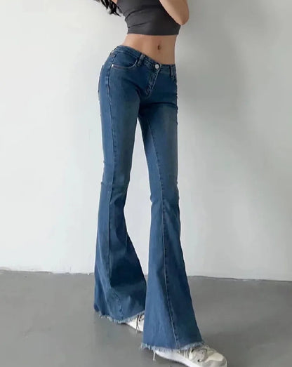 Person wearing blue flared jeans and a black crop top on a plain background