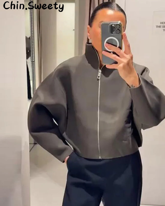Person wearing a gray jacket taking a mirror selfie.