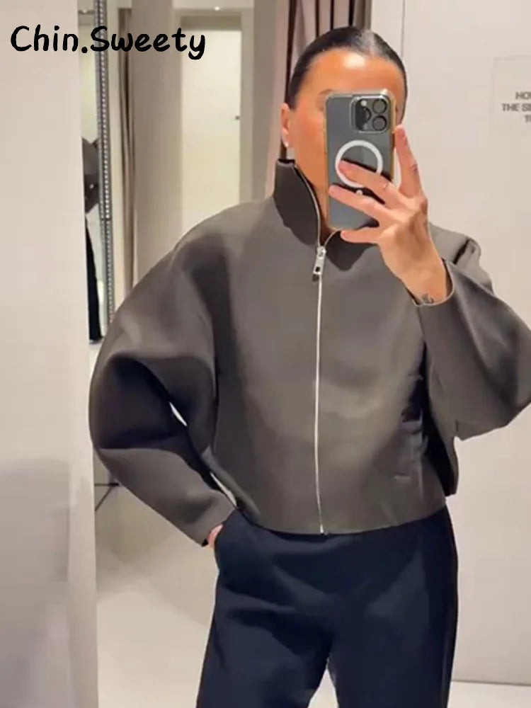 Person wearing a gray jacket taking a mirror selfie.