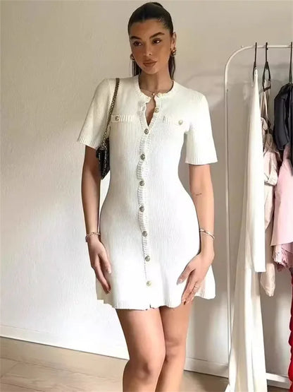 Woman wearing a white dress with a brand logo in a room with clothing racks.