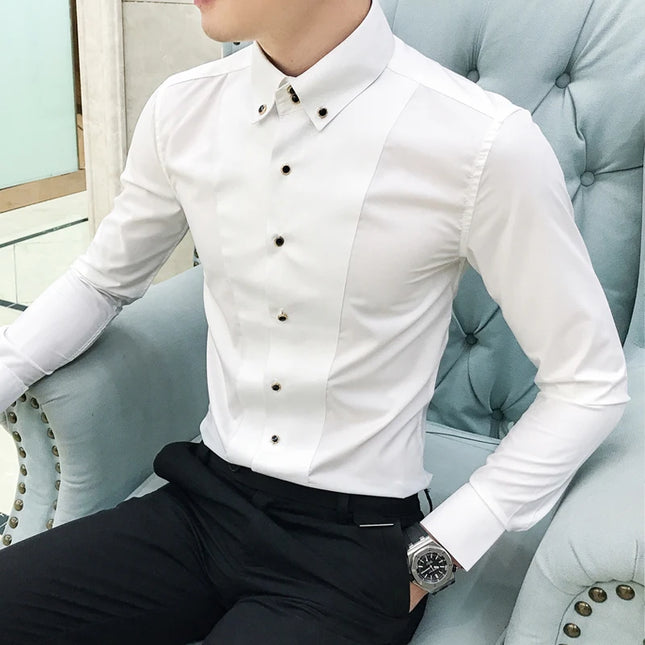 Person wearing a white dress shirt with black buttons and black pants, sitting on a light blue couch.