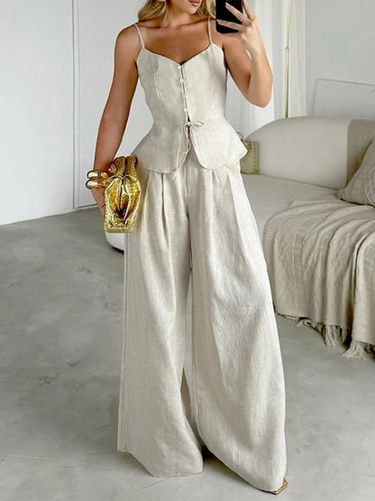 Woman in a beige jumpsuit taking a mirror selfie in a room with a couch.