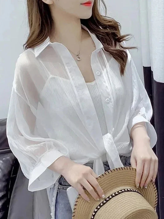 Woman wearing a white sheer blouse with a blurred background