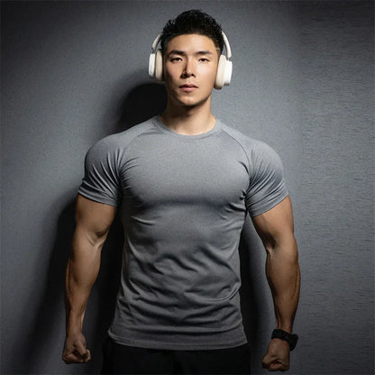 Man wearing a gray t-shirt and white headphones against a dark background