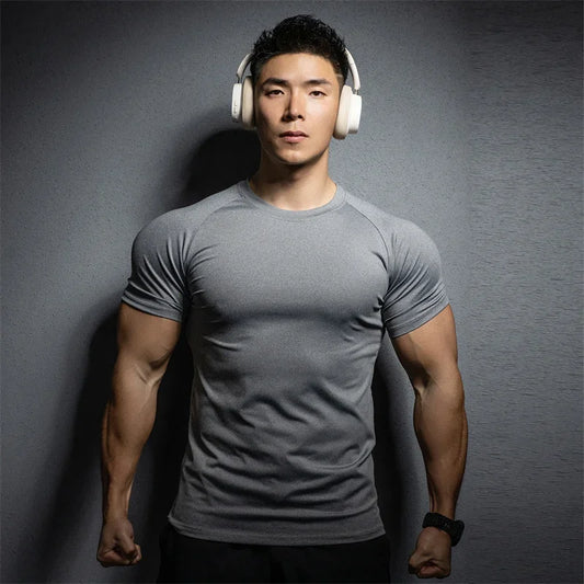 Man wearing a gray t-shirt and white headphones against a dark background