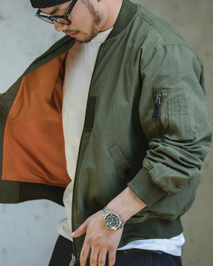 Man wearing a green bomber jacket with a neutral background