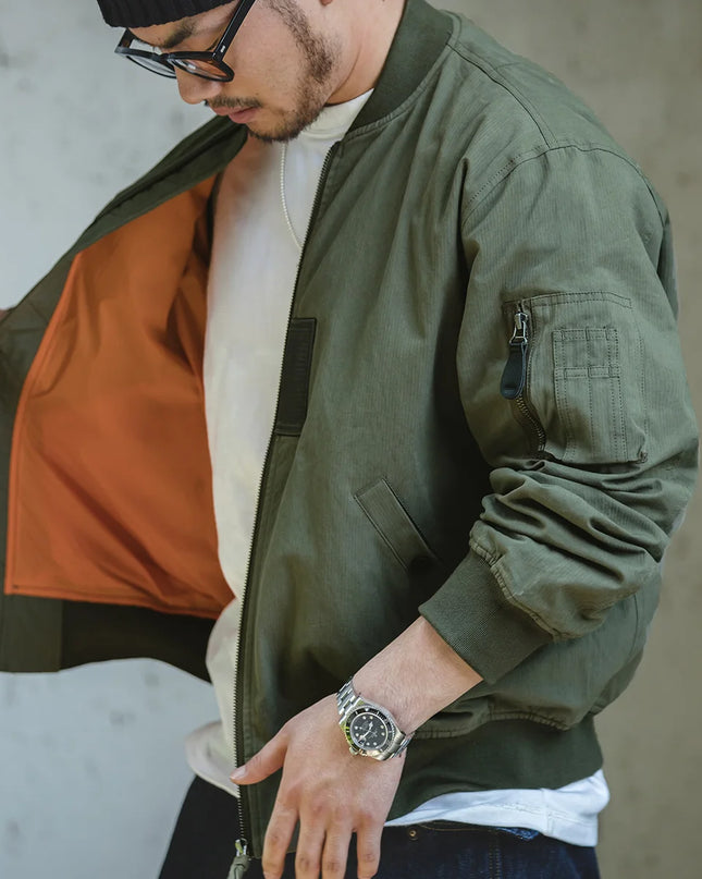 Man wearing a green bomber jacket with a neutral background